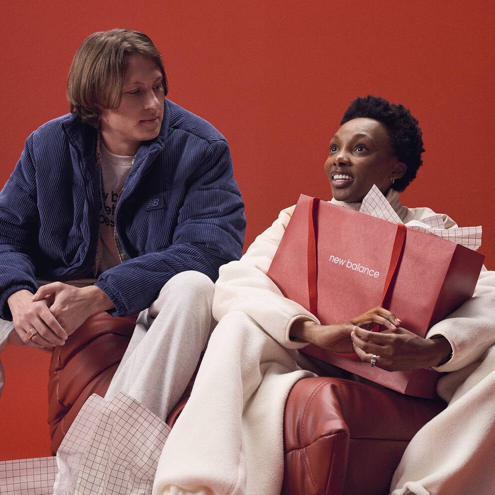 A person holding a New Balance branded bag with another person looking at them